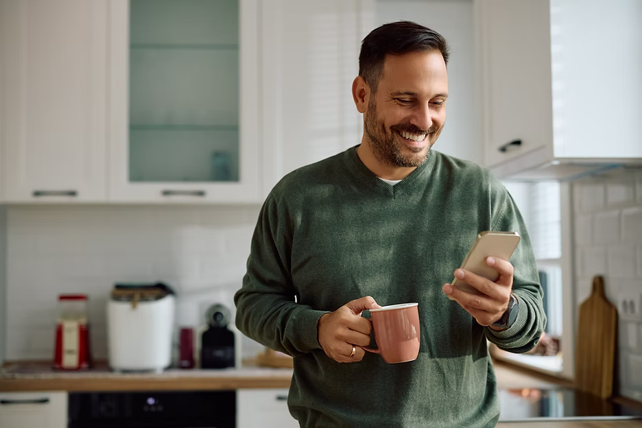 Homeowner checking smartphone while enjoying reliable hot water from a Daikin heat pump hot water system